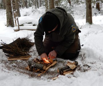 Torbjörn selin sitter på knä och tänder en liten eld i snön