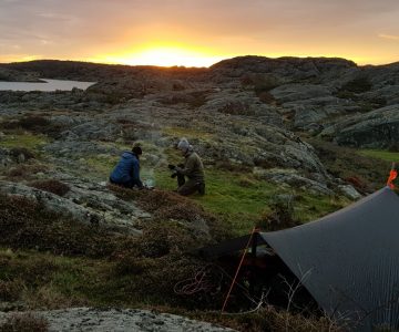 Coastal survivors making breakfast ifront of shelter, sun is rising